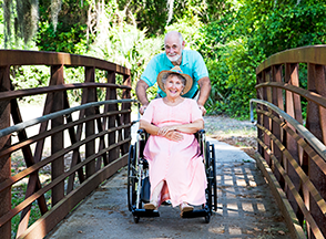 elderly hudband pushing wife in wheelchair